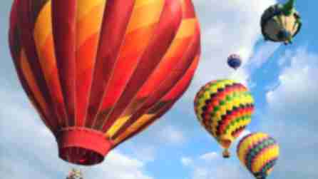 Multicolored hot air balloons flying above head at Spiedie Fest in Binghamton on a partly cloudy summer day