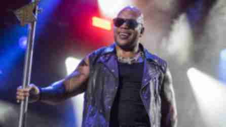 Flo Rida, wearing a black leather vest, sunglasses, and silver chains, holds a microphone stand illuminated by dramatic stage lighting and fog while performing on the Suburban Park Stage at the Great New York State Fair in Syracuse on Thursday, August, 29, 2024.