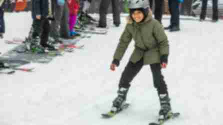 A child learning to ski down a snowy hill