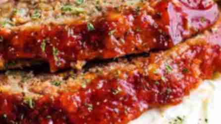 two slices of meatloaf on top of mashed potatoes