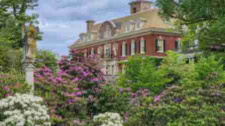 Brick Exterior of the Old Westbury House surrounded by bright green plants and pink and white flowers