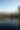 From the bank of a pond in Jones State Forest, the camera overlooks the water reflecting a horizon of thick pine trees. The sky is bright blue.