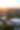 An aerial view of The Woodlands, Texas, featuring the Pavilion in the lower right of the frame. The Waterway wraps around the Pavilion from the left, leading into various business and residential areas before reaching Lake Woodlands. The sun is setting beautifully on the horizon.
