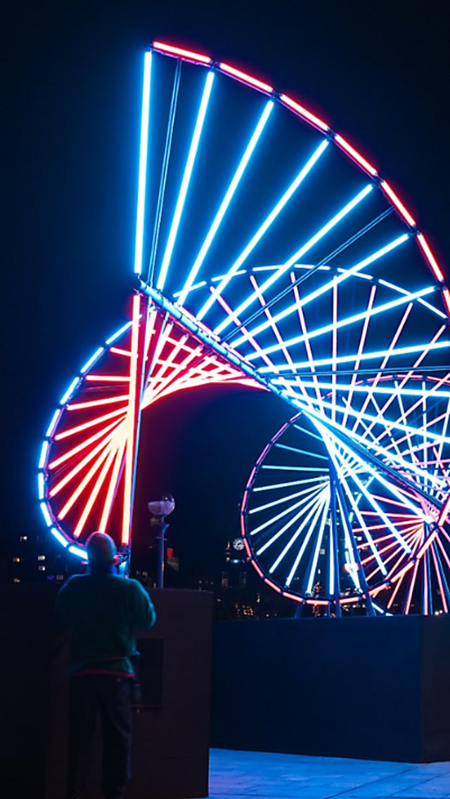 A large DNA inspired light installation that is lit up in blue and res.