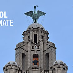 The top of the Royal Liver Building with the Liver Bird at the top. Someone dressed as The Batman is stood on a platform as they are filmed for a movie.