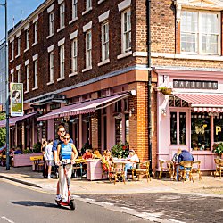 Two people on a Voi Scooter in the Georgian Quarter on a sunny day