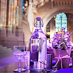 A close up of a table decorated with a lavender plant and bathed in purple light. The table is inside Liverpool's Anglican Cathedral