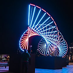 A large DNA inspired light installation that is lit up in blue and res.