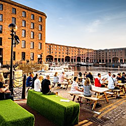People sitting outside at the Royal Albert Dock in summertime