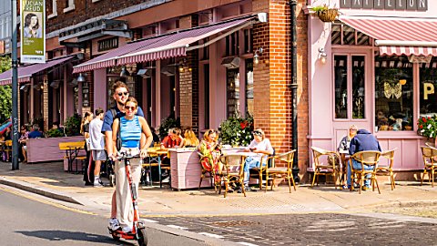 Two people on a Voi Scooter in the Georgian Quarter on a sunny day