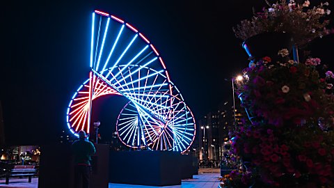 A large DNA inspired light installation that is lit up in blue and res.