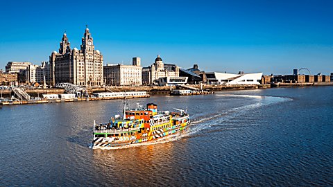 A ferry on the River Mersey with the Liverpool skyline behind it.