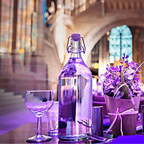 A close up of a table decorated with a lavender plant and bathed in purple light. The table is inside Liverpool's Anglican Cathedral