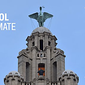 The top of the Royal Liver Building with the Liver Bird at the top. Someone dressed as The Batman is stood on a platform as they are filmed for a movie.