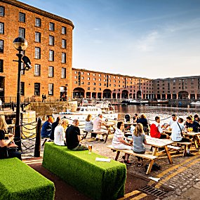 People sitting outside at the Royal Albert Dock in summertime