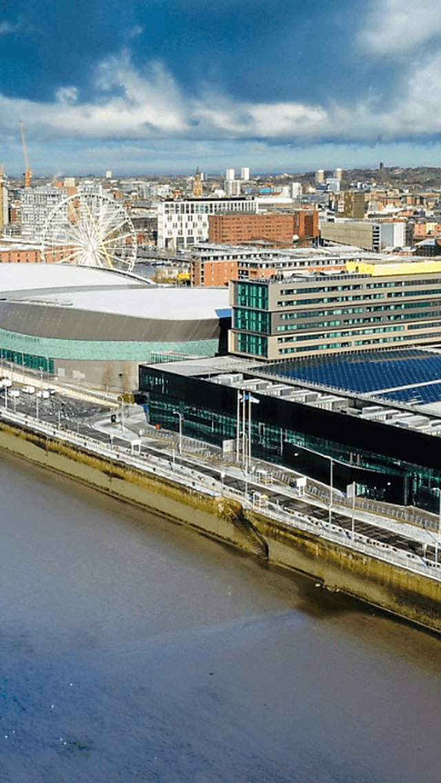 A drone shot taken from the river side overlooking the M&S Bank Arena and Exhibition Centre. The Royal Albert Dock buildings can be seen on the front and behind the arena. It is
