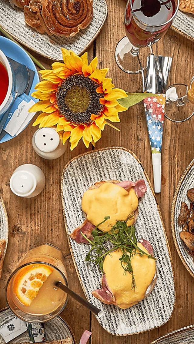 A table from a birds eye view with many places of breakfast food and drinks.