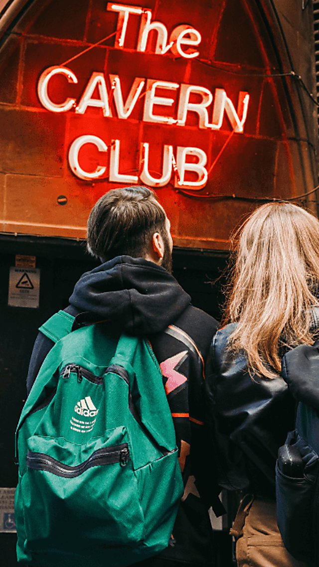People standing outside the Cavern Club with the sign illuminated