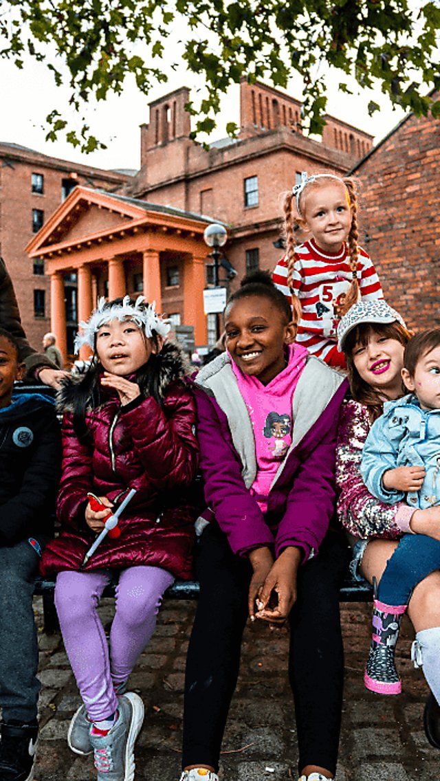 Children sitting with parents smiling at the Royal Albert Dock