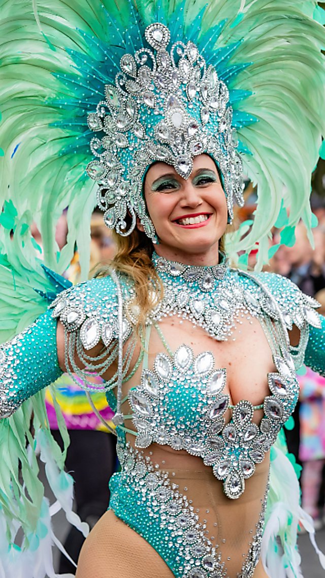 A lady dressed in carnival clothing with a large, mint green headdress