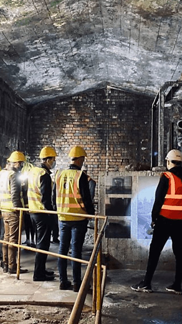 Inside the Mersey Tunnel Tour. People are wearing high vis vests and hard hats and look to be underground.