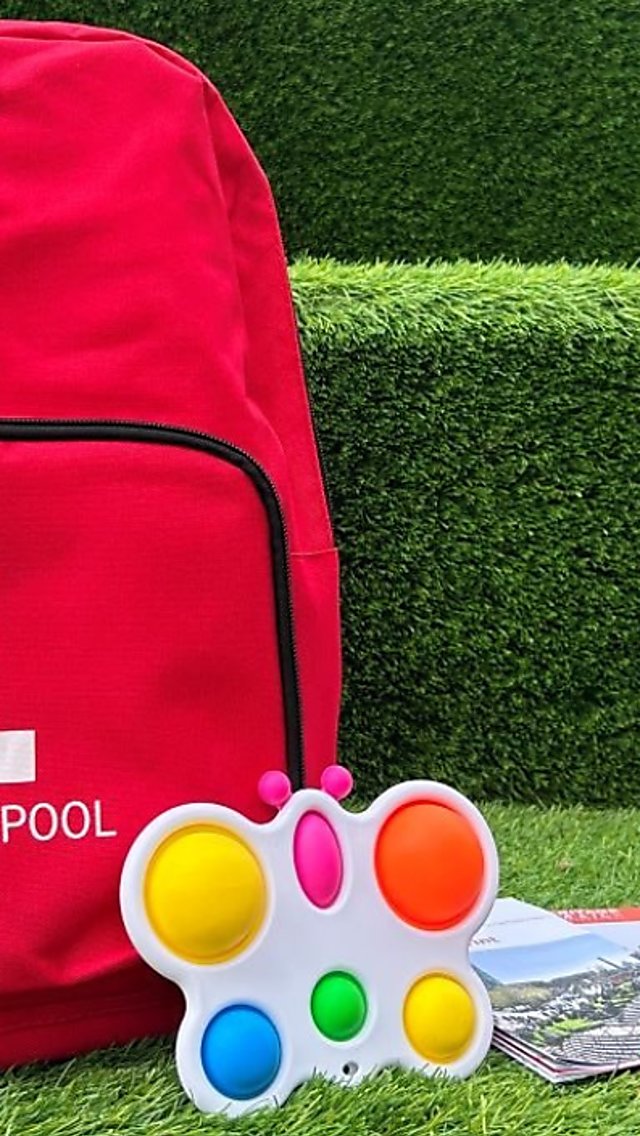 A red bag with Liverpool ONE logo on it, along with fidget toys and ear defenders.