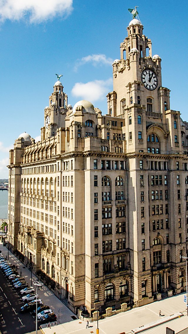 The Royal Liver Building exterior with a bright blue sky and a cruise in the distance.