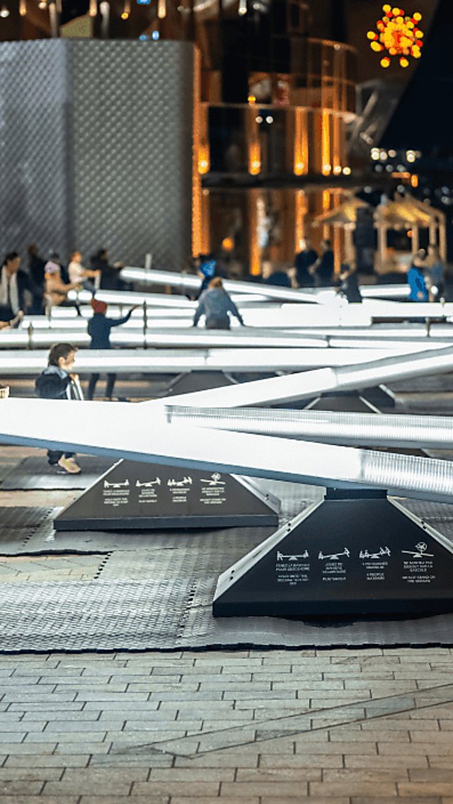 Children playing on the installation with bright lights shining in a dark night.