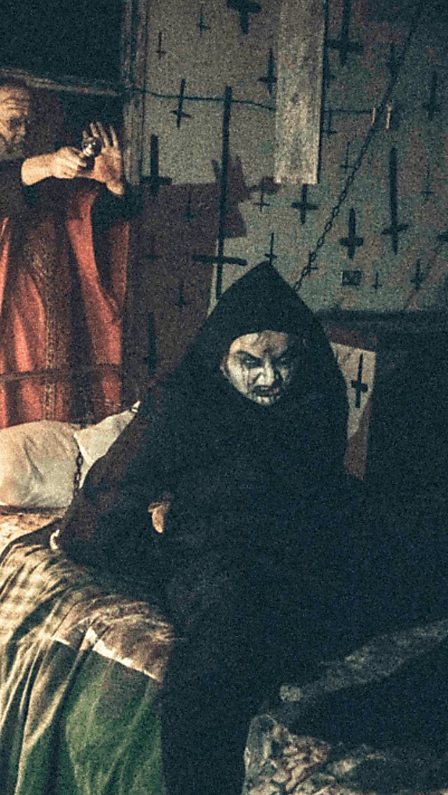 Scary Halloween themed characters in a dark room covered in crucifixes