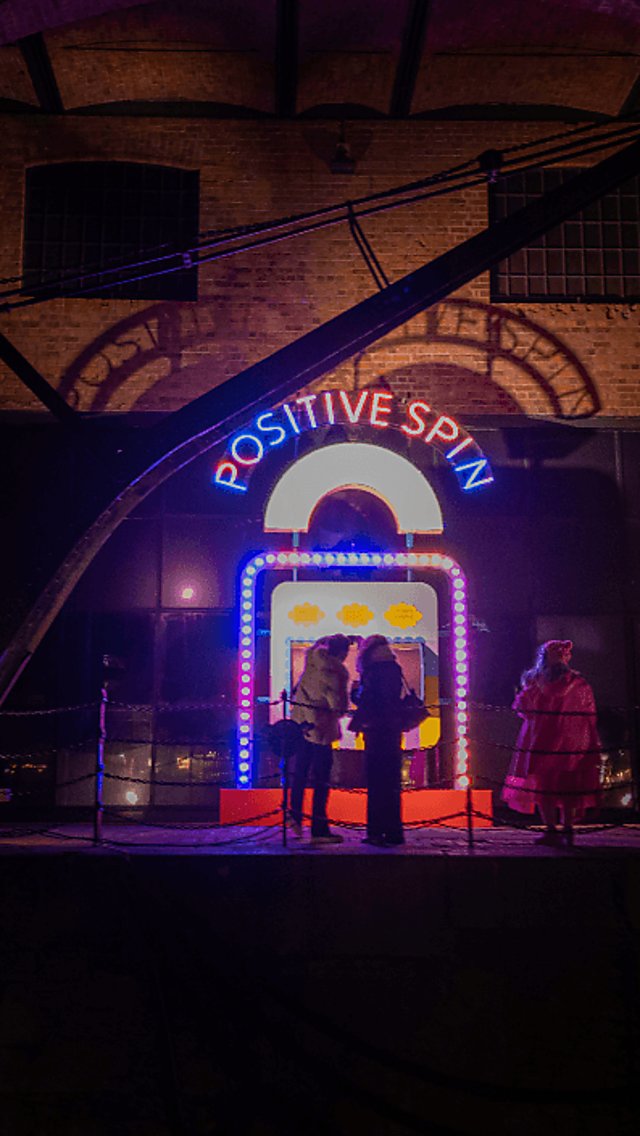 A light installation that says 'Positive Spin' with several different colours in red, yellow, blue and green.