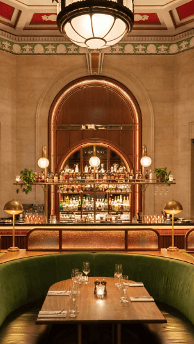 A landscape shot of an art deco interior bar with a large vaulted ceiling with red and green details.