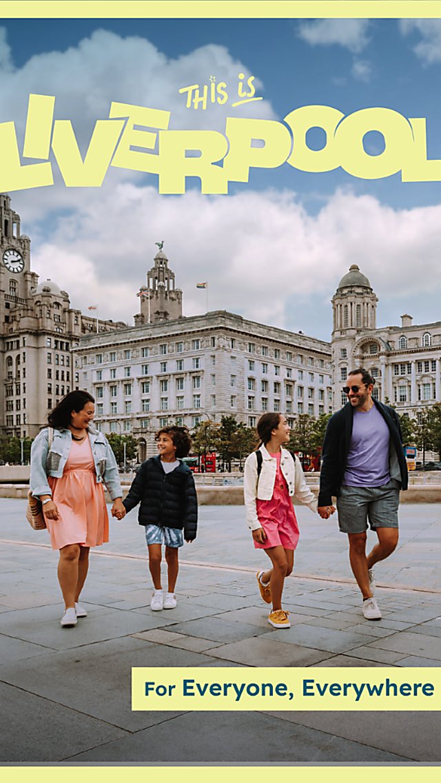 A family of four walking along Pier Head in Liverpool with three heritage buildings in the background. There are two adults and two children. There is yellow text that says 'Liverpool' across the top.