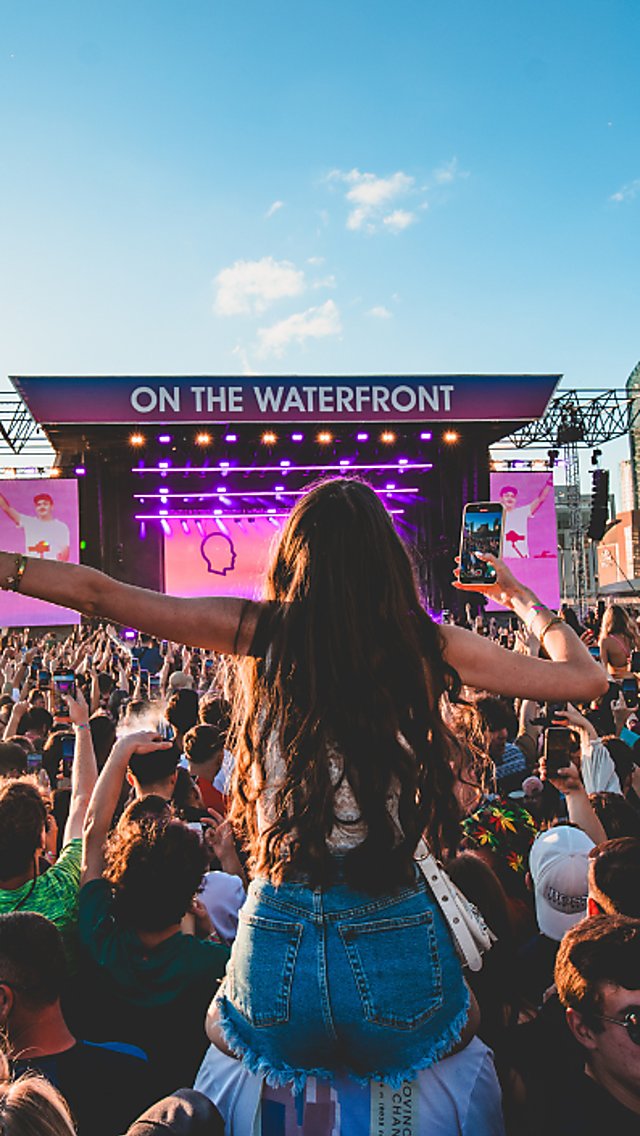 A girl on someones shoulders at a festival on Liverpool Waterfront on a sunny day