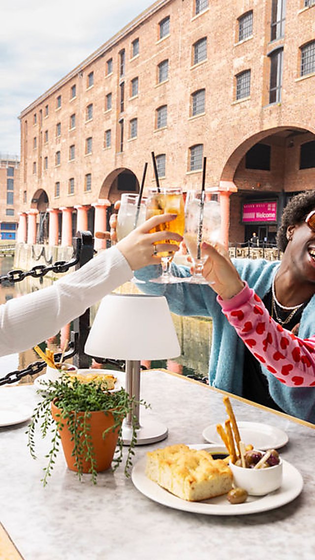 Three people sit at a table at the Royal Albert Dock