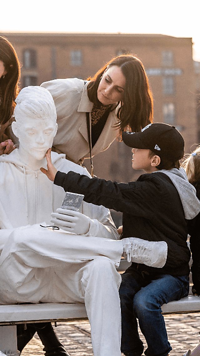 People engaging with a statue on a bench