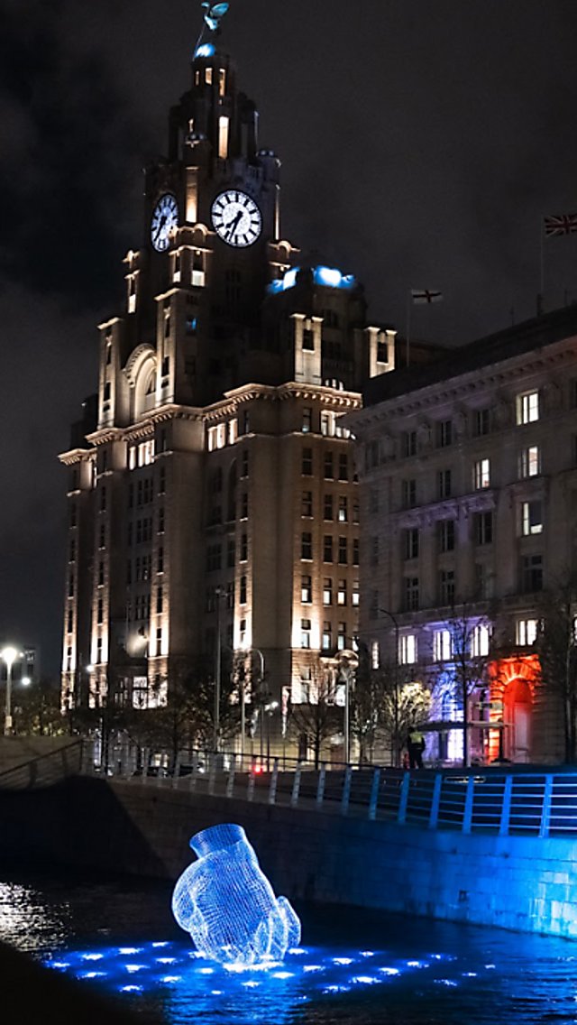 An artwork of a hand that looks like it is floating on water with lights around it.