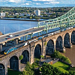 An Avanti West Coast train on a bridge going over a river.
