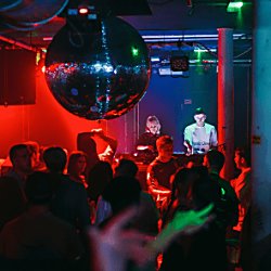 People in a club with a giant disco ball and people dancing to DJs