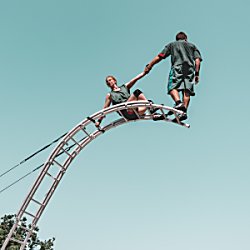 Two people on a curved ladder standing at the top of it.