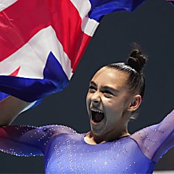 A gymnast wearing a blue leotard with red sleeves holding a Union Jack flag.
