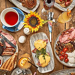 A table from a birds eye view with many places of breakfast food and drinks.