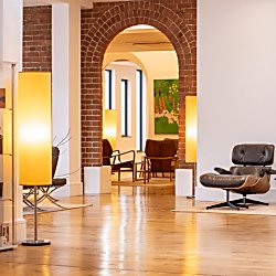 A modern, light lobby space with white walls, light oak flooring, an exposed brick archway and minimal decor and furnishings.