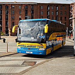 The 'Magical Mystery Tour' coach on Liverpool Albert Dock. The coach is bright yellow and green with rainbow writing on the side