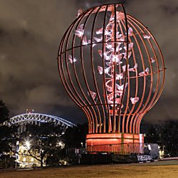 A large light sculpture which looks like a light blub with moths flying around it.