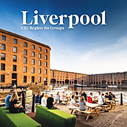 A group of people sitting on summer benches at Royal Albert Docks with the sun shining in the background.