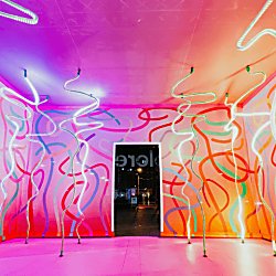 A large pink room with ribbon patterns in colours on the walls and in led lights from the ceiling