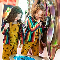 Two children smiling and looking at a digital screen on the floor.