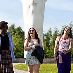 3 people walking and laughing in front of a large white sculpture