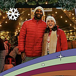 Two people stood infront of a Christmas bar with decorations around them.