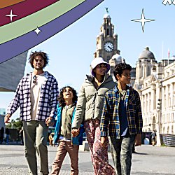 A family of four with two adults and two children walking along Liverpool's Pier Head.